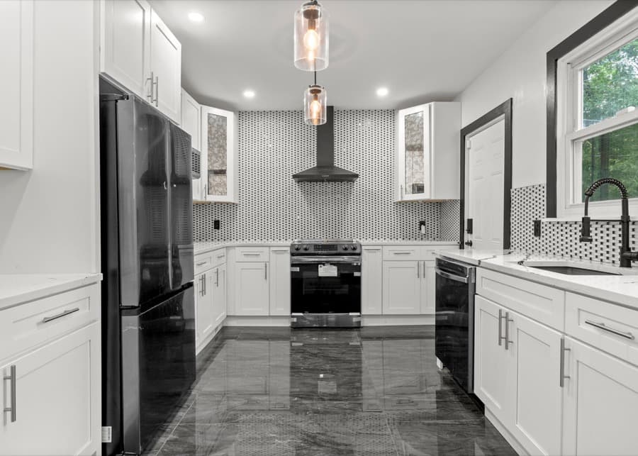 White kitchen with a patterned backsplash and black appliances